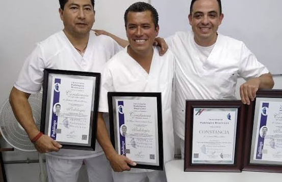 Tres egresados del Instituto Podológico Mexicano con uniforme blanco mostrando sus constancias enmarcadas